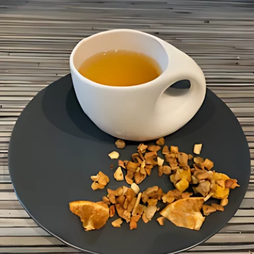 Früchtetee Pyrange in weißer Tasse aufgegossen und lose auf grauem Teller vor gestreiftem Holzhintergrund