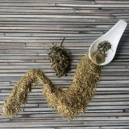 Apoyar mit Brennnessel mit weißem Porzellanlöffel auf gestreifter Arbeitsplatte.