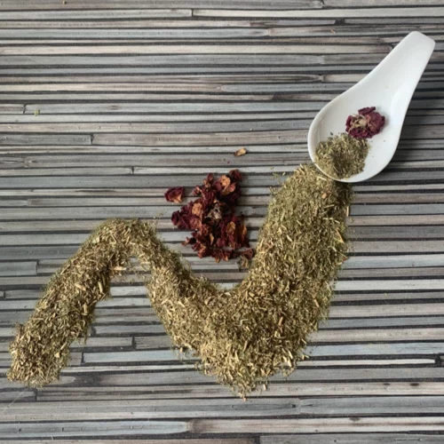 Apoyar mit Rosenblüten mit weißem Porzellanlöffel auf gestreifter Arbeitsplatte.