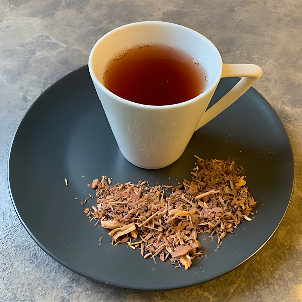 Nahaufnahme einer weißen Teetasse mit braunem Inhalt und losem Tee auf einer marmorierten Arbeitsplatte.