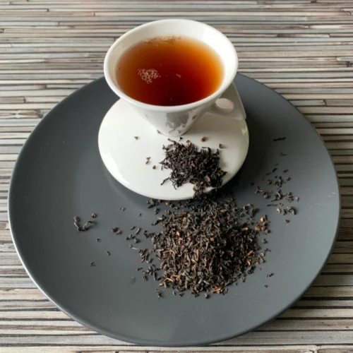 English Breakfast Broken auf grauem Teller mit weißer Tasse vor gestreiftem Holzhintergrund