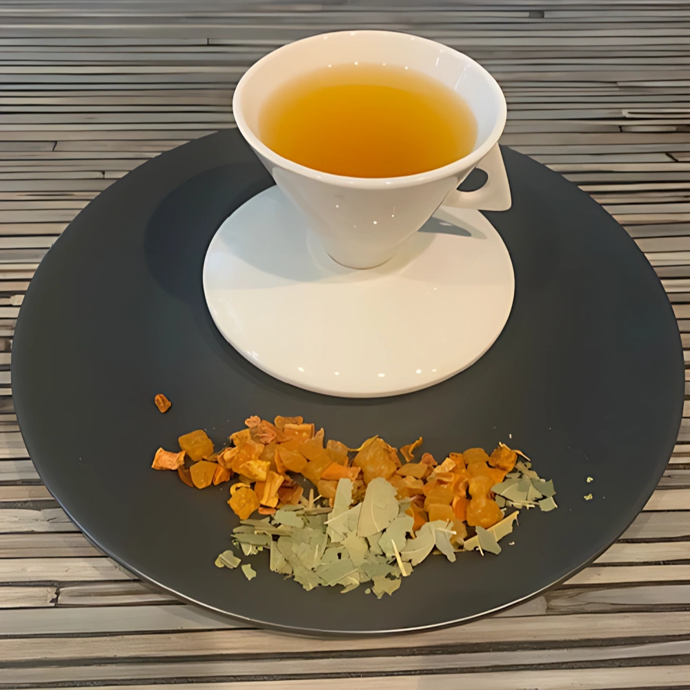 Früchtetee Anabama Mangoblätter in weißer Tasse auf grauem Teller vor gestreiftem Holzhintergrund