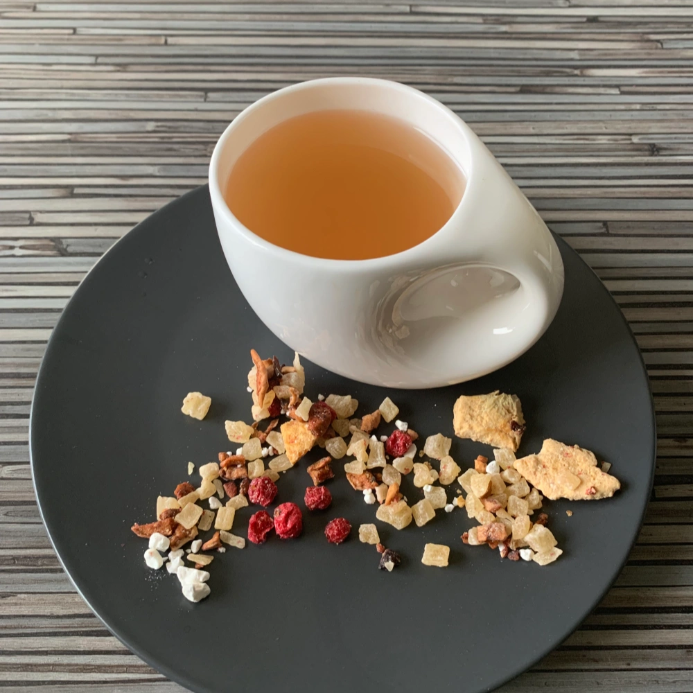 Früchtetee Bitterlimonade Grapefruit Zitronen in weißer Tasse auf grauem Teller vor gestreiftem Holzhintergrund