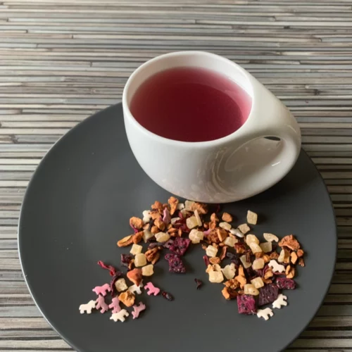 Früchtetee Fang mich doch in weißer Tasse auf grauem Teller vor gestreiftem Holzhintergrund