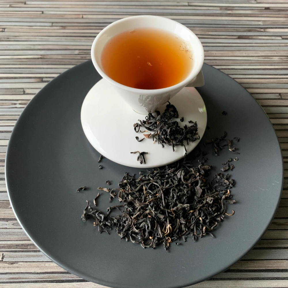 Java Premium OP auf grauem Teller mit weißer Tasse vor gestreiftem Holzhintergrund