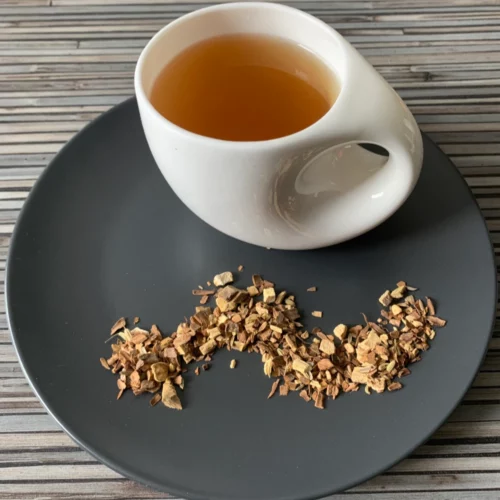 Kräutertee Vata ohne Aroma in Teetasse, lose Kräutermischung mit Zimt, Orangenschalen und Kardamom auf gestreiftem Holzuntergrund