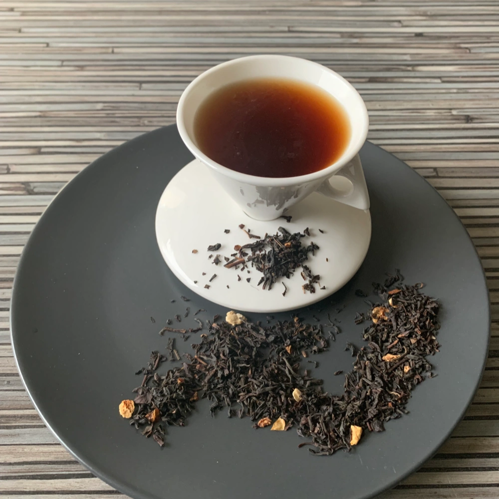 Schwarztee Lemon Zitronentee mit Zitronenschalen in weißer Tasse auf gestreiftem Untergrund