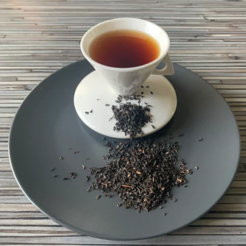 Ostfriesland Auslese Brokenmischung auf grauem Teller mit weißer Tasse vor gestreiftem Holzhintergrund