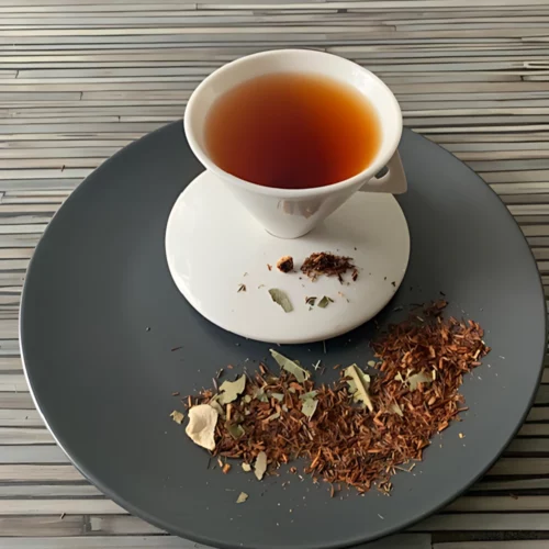 Rotbusch Greylicius Mangoblätter mit Rotbuschtee und Zitronenschalen und kupferfarbener Tassenfarbe in weißer Teetasse auf gestreiftem Hintergrund