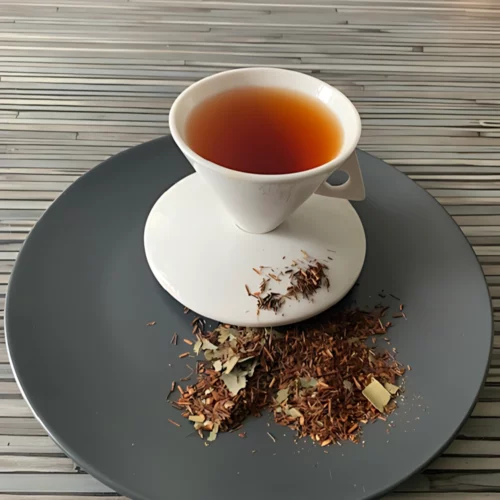 Rotbusch Manilli Mangoblätter mit Rooibos und grünen Mangoblättern, kupferfarbene Tassenfarbe in weißer Teetasse auf gestreiftem Hintergrund