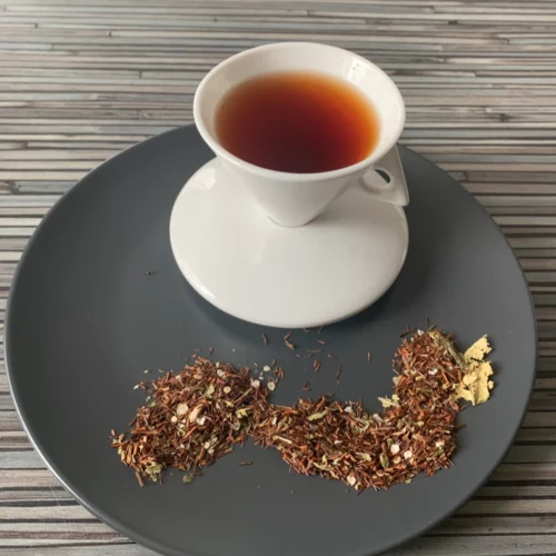 Rotbusch Quinoa Granatapfel mit Rotbuschtee und Quinoa, kupferfarbene Tassenfarbe in weißer Teetasse auf gestreiftem Hintergrund