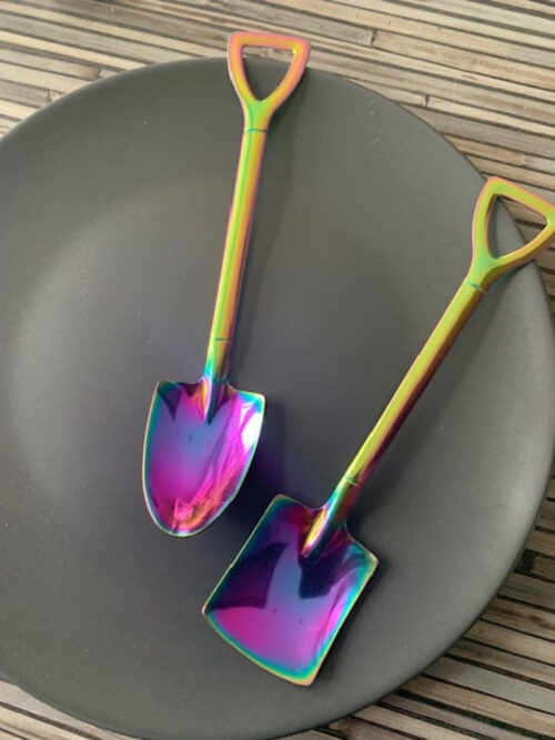 Teelöffel aus Edelstahl bunt Form von Schaufel und Spaten auf dunklemn Teller.