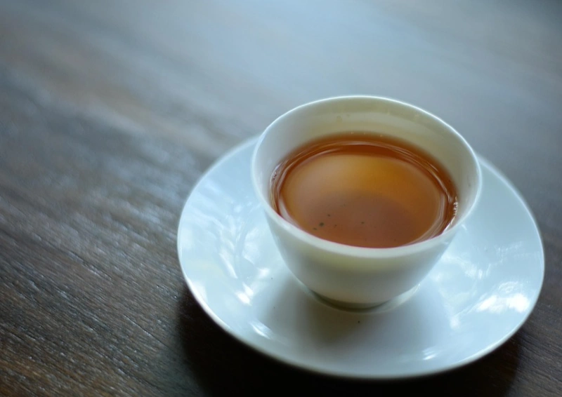 Vietnam Black Lion in einer Teetasse angeboten die auf einem Holztisch ist.