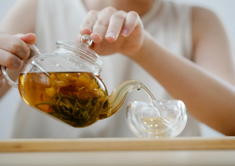 Blooming Tea Ocean Pearl wird von einer Frau eingeschenkt.