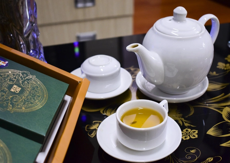 China Wu Lu in der Tasse eingeschenkt, daneben eine Teekanne.