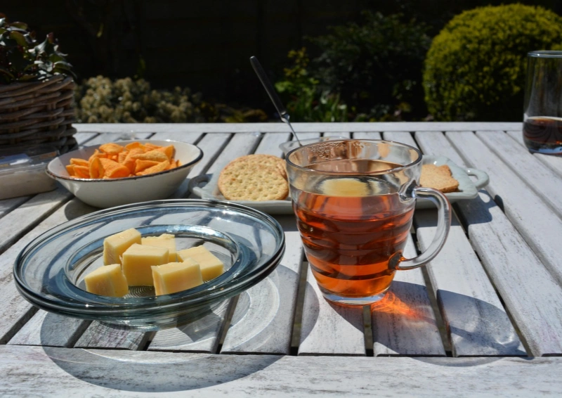 Schwarztee Sikkim Temi angerichtet im Glas mit einem Teller Käse.