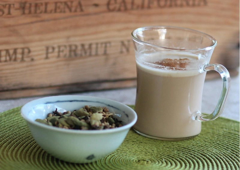 Indischer Masala Chai mit Kardamom und Gewürzen im Glas serviert