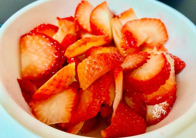 Rotbuschtee Grün Erdbeer Sahne mit geschnittenen Erdbeeren