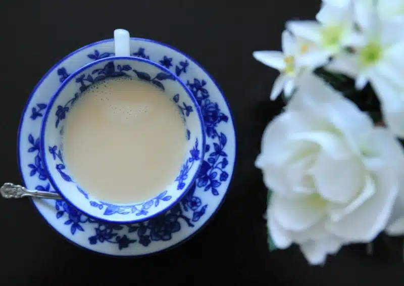 Ayurveda Mithi Chai in einer blaun-weißen Tasse mit Milch