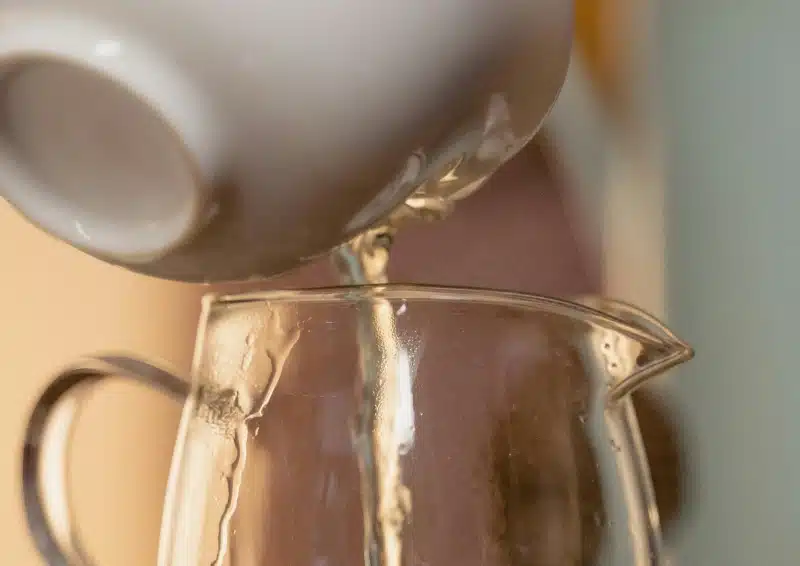 Weißer Tee Safran Pfingstrose wird aus einer weißen Kanne eingeschenkt