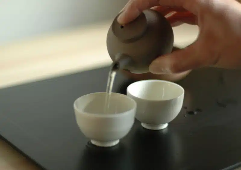 Weißer Tee Darjeeling Ambootia wird aus einer Tonkanne eingeschenkt